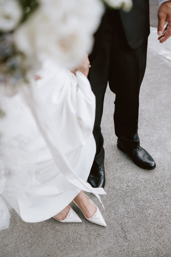 Close-up of the bride’s Prada heels and the groom’s polished shoes as they stand together on the courtyard steps at Cafe Julia, a stylish and storytelling wedding detail.