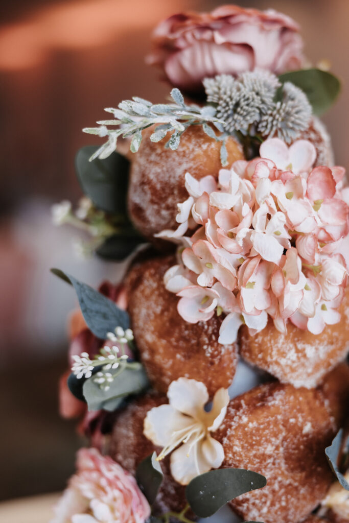 A wedding dessert tower made of malasadas decorated with pink flowers, greenery, and delicate blooms at The Queen Kapiolani Hotel in Waikiki, Honolulu.