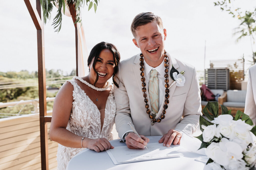 Couple smiling signing their marriage certificate at the Deck Waikiki